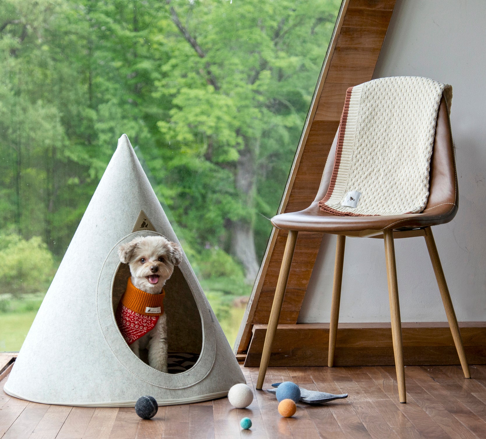 A dog resting inside the Nooee Pet Buddy Cave in Cream, set in a modern living space.