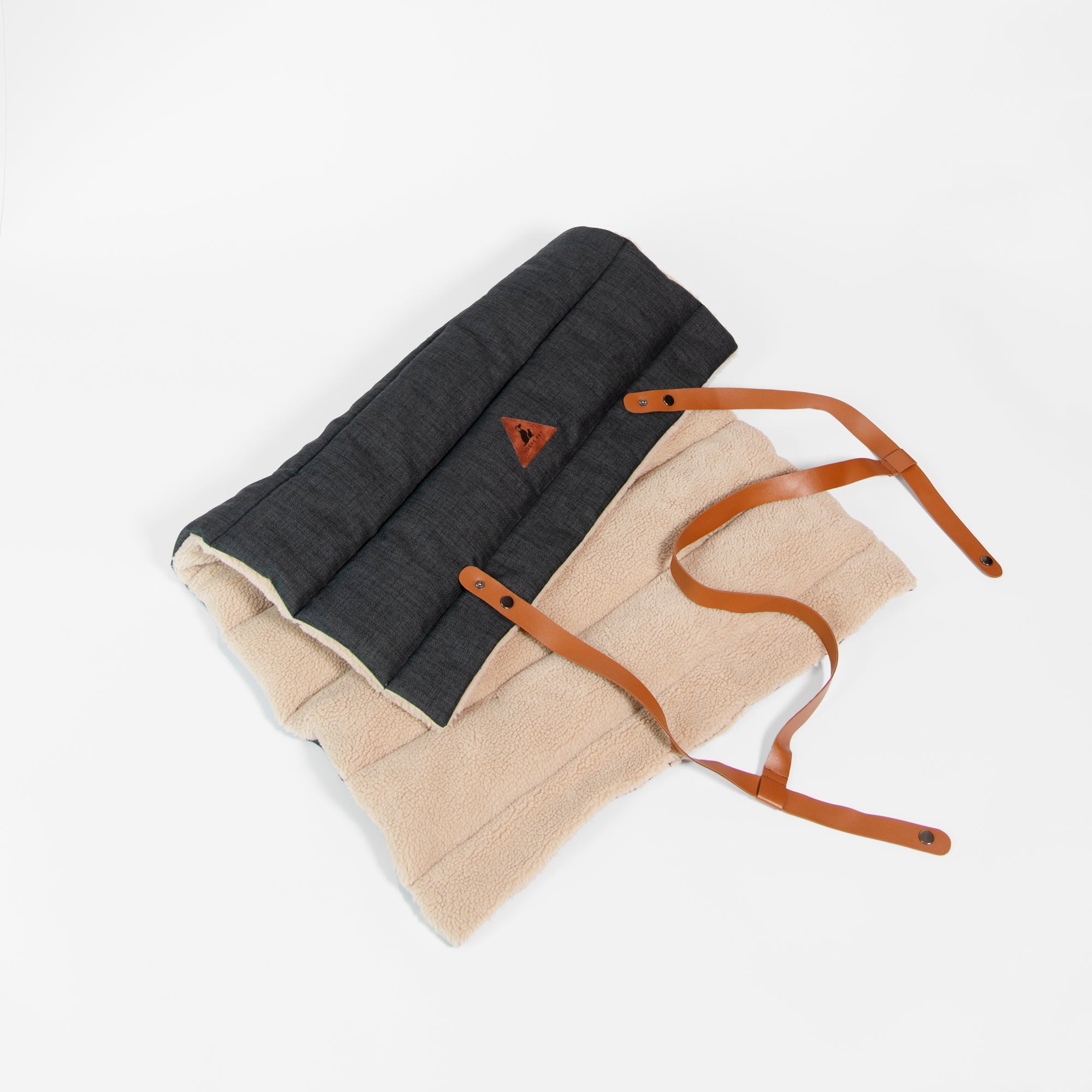 Nooee Pet Jack Mat partially unrolled to show both the soft beige sherpa side and the dark quilted fabric side, with brown vegan leather straps extended for carrying.