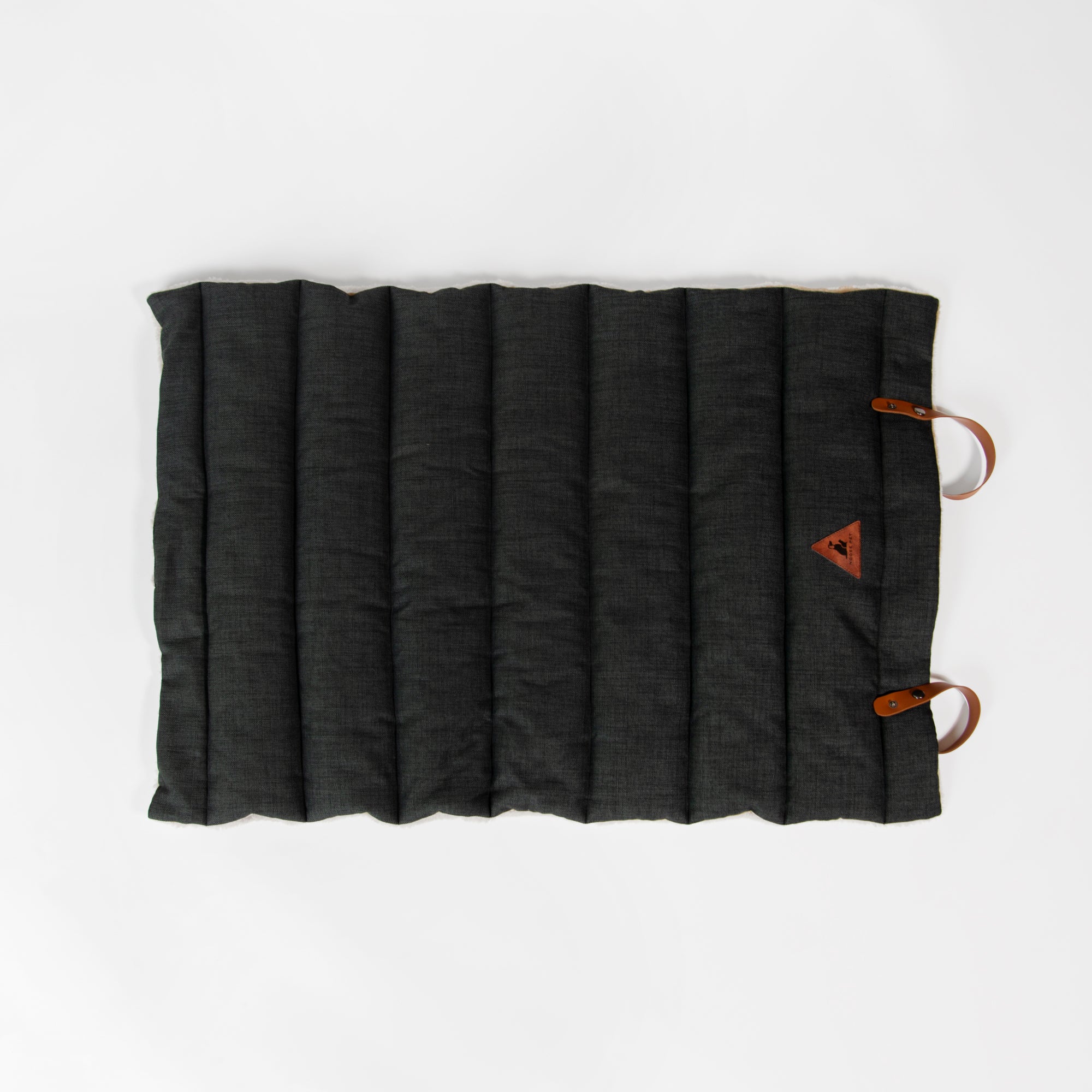Flat-lay of Nooee Pet Jack Mat with black quilted fabric, vegan leather handles, and stitched Nooee Pet logo patch on the corner.