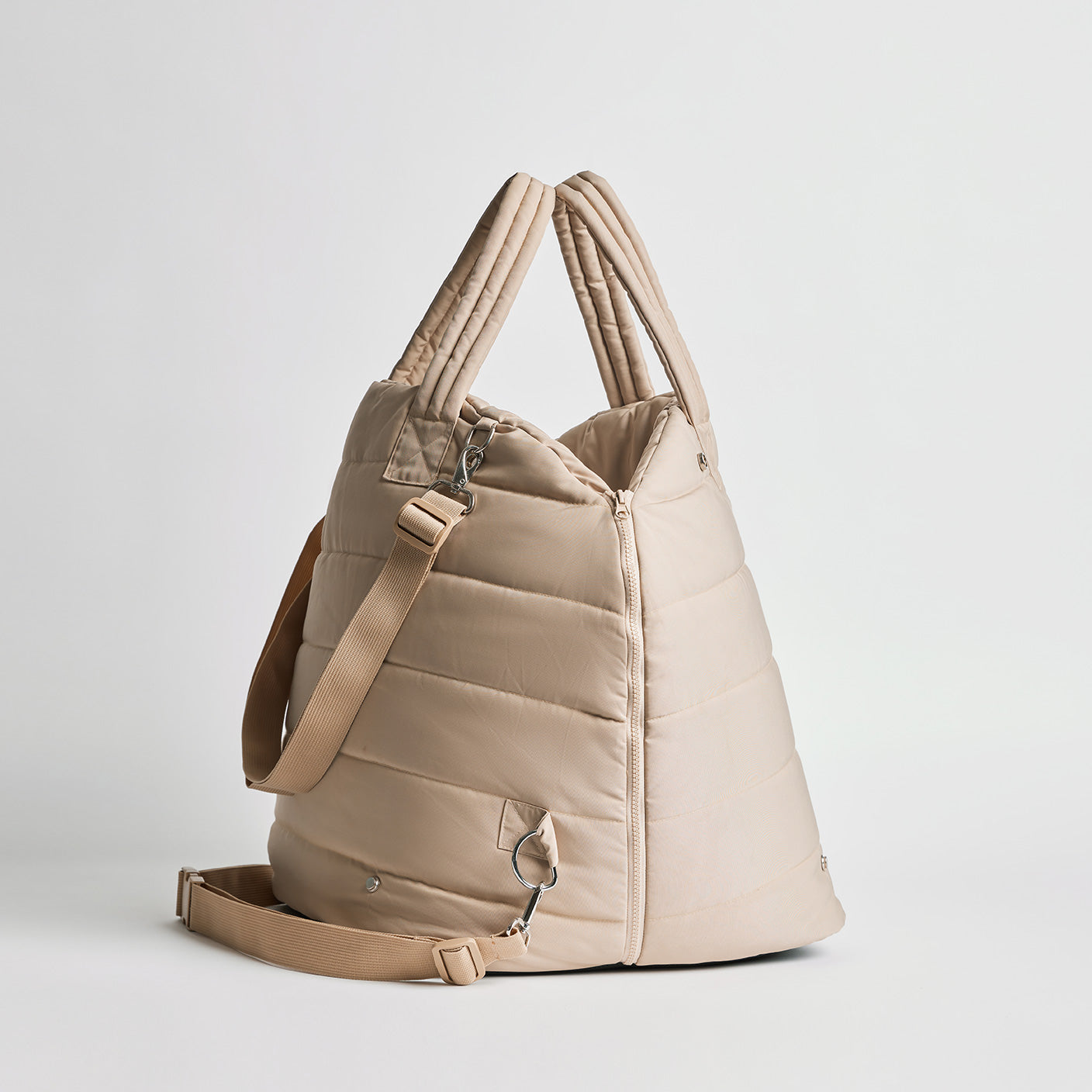Side view of the Nooee Pet Lola Car Seat in cream nylon, showing adjustable shoulder strap, zippered closure, and soft quilted structure.
