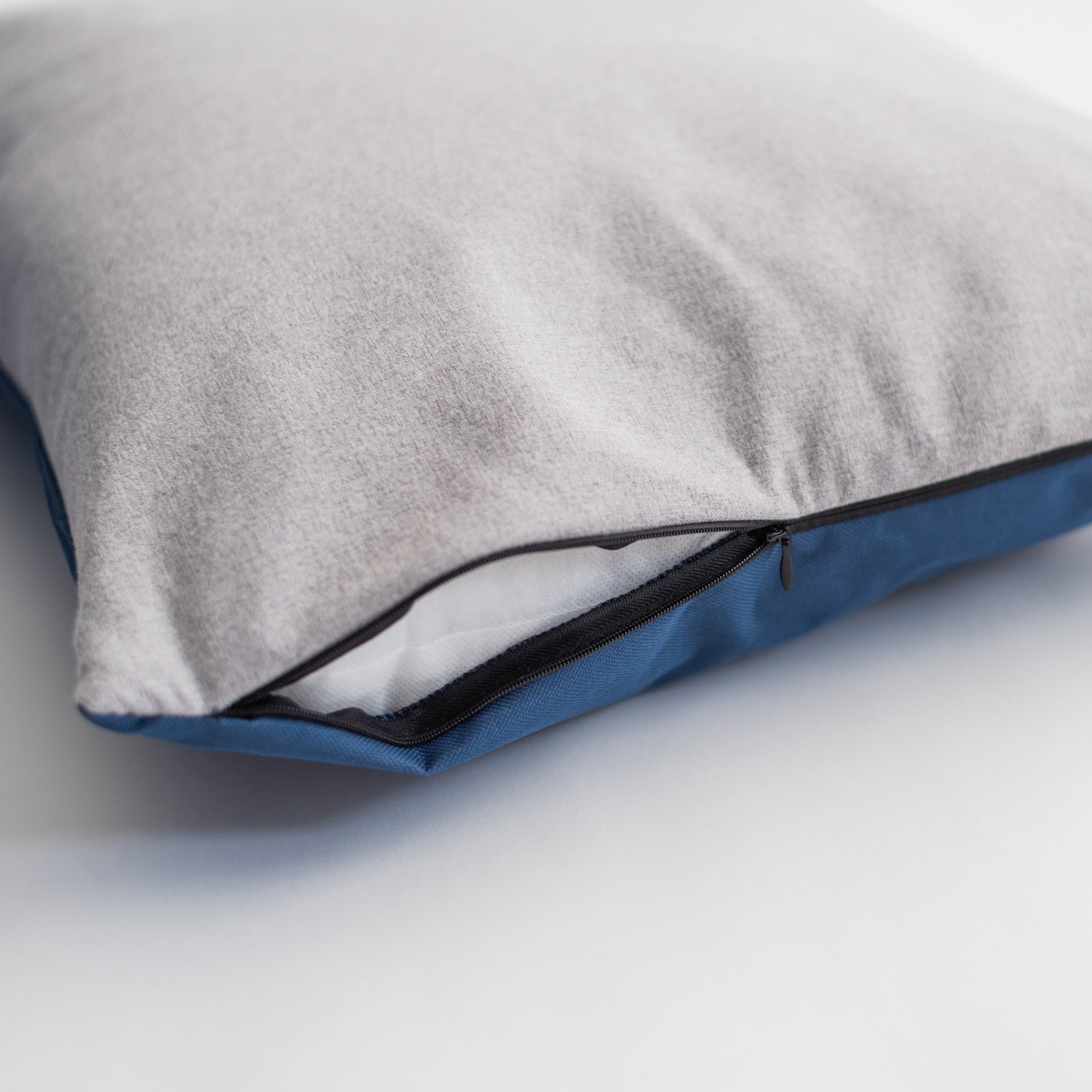 Close-up of the Nooee Pet Car Seat Charlie's removable cushion, showing the zippered opening with a two-tone design—light gray on top and navy blue on the bottom—revealing the inner insert for easy cleaning.