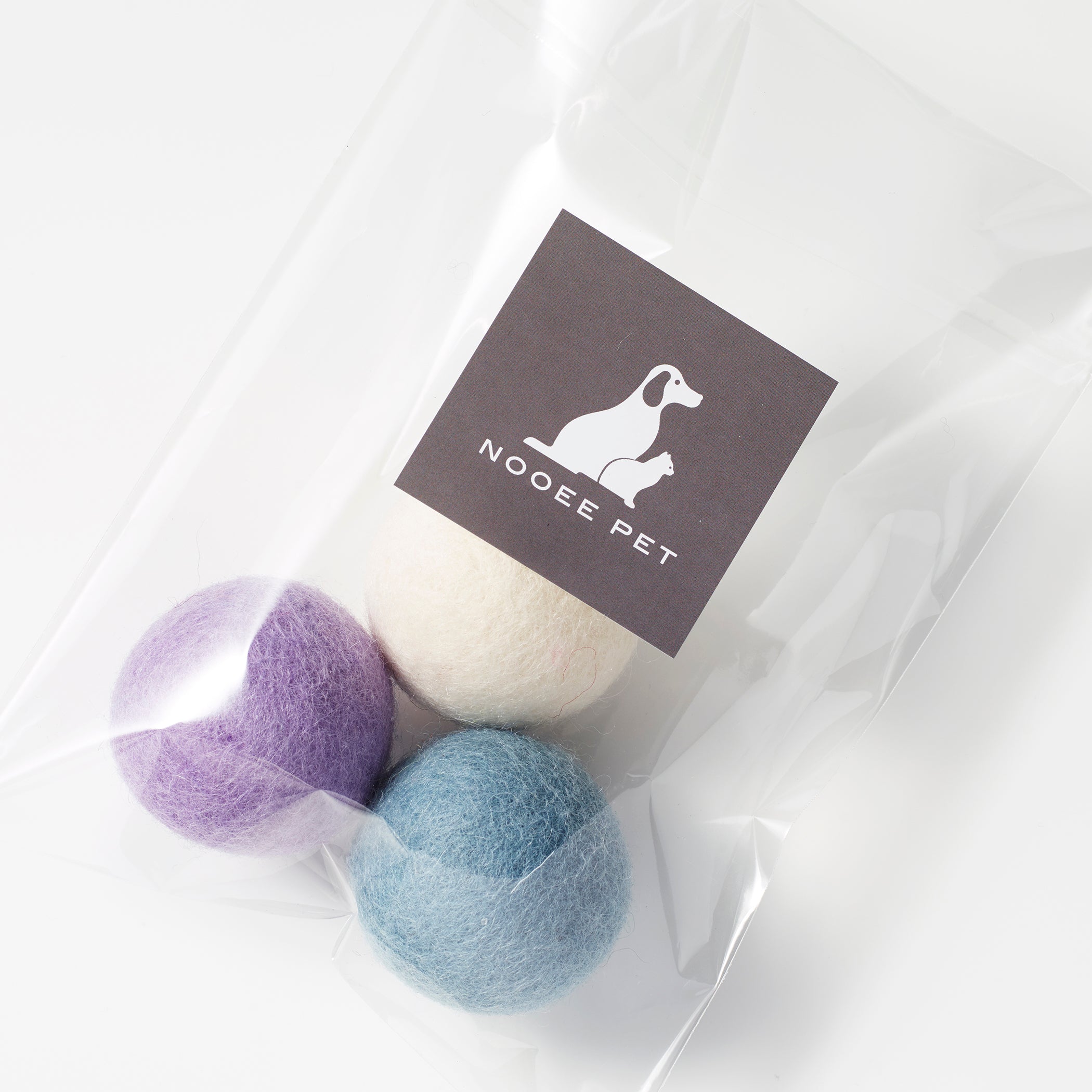 Top view of pastel-colored wool toy balls in a branded Nooee Pet pouch.