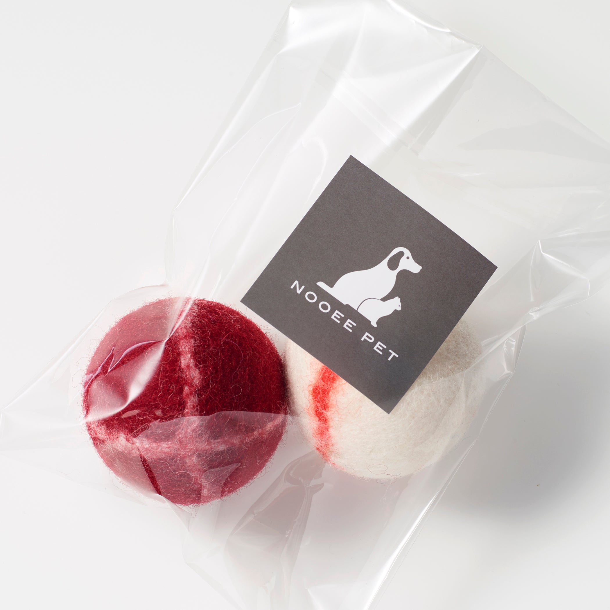 Two wool toy balls (red and cream) in Nooee Pet packaging