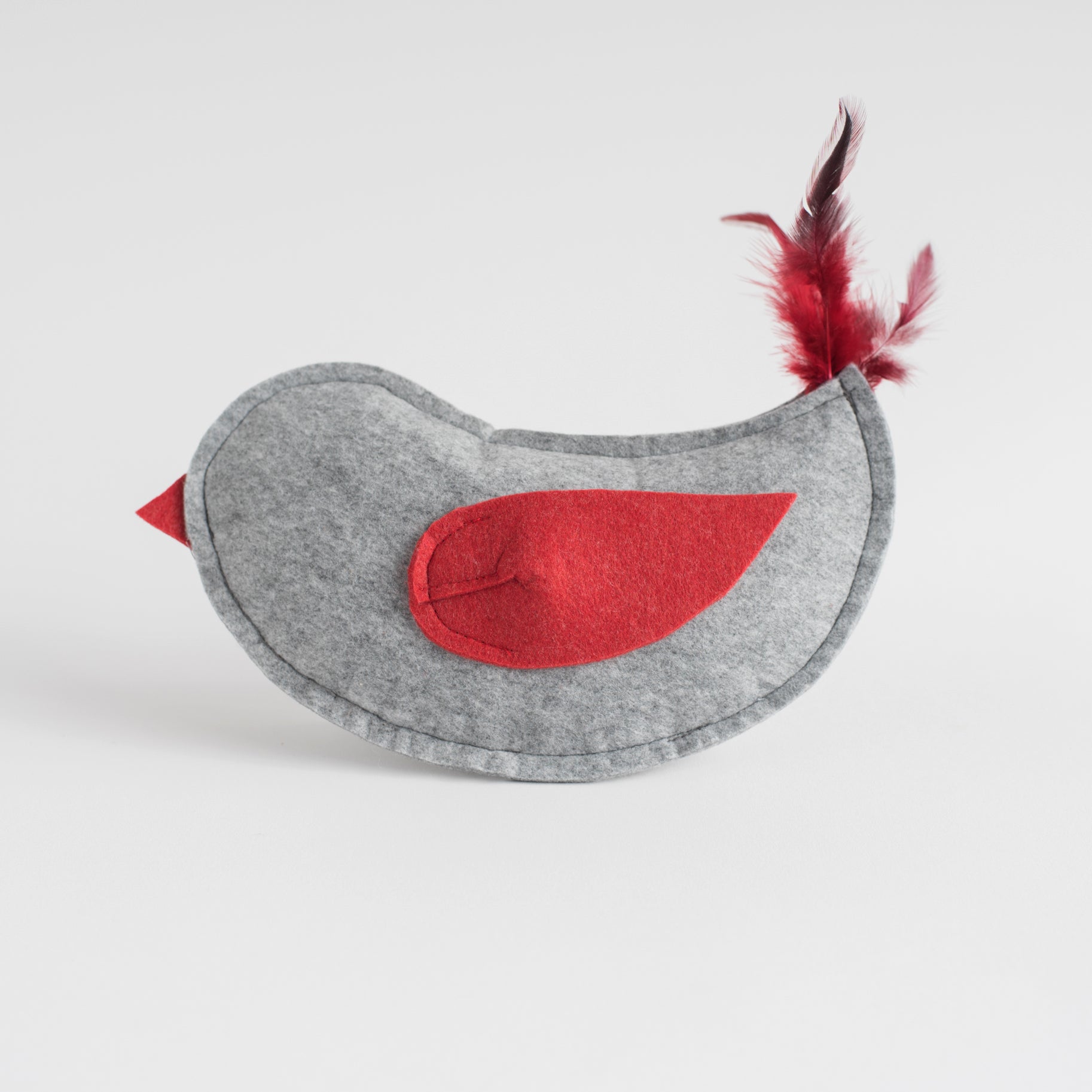 Gray felt bird toy with red felt wing and beak, accented by dark red feathers on the tail, displayed on a white background.