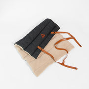 Nooee Pet Jack Mat partially unrolled to show both the soft beige sherpa side and the dark quilted fabric side, with brown vegan leather straps extended for carrying.