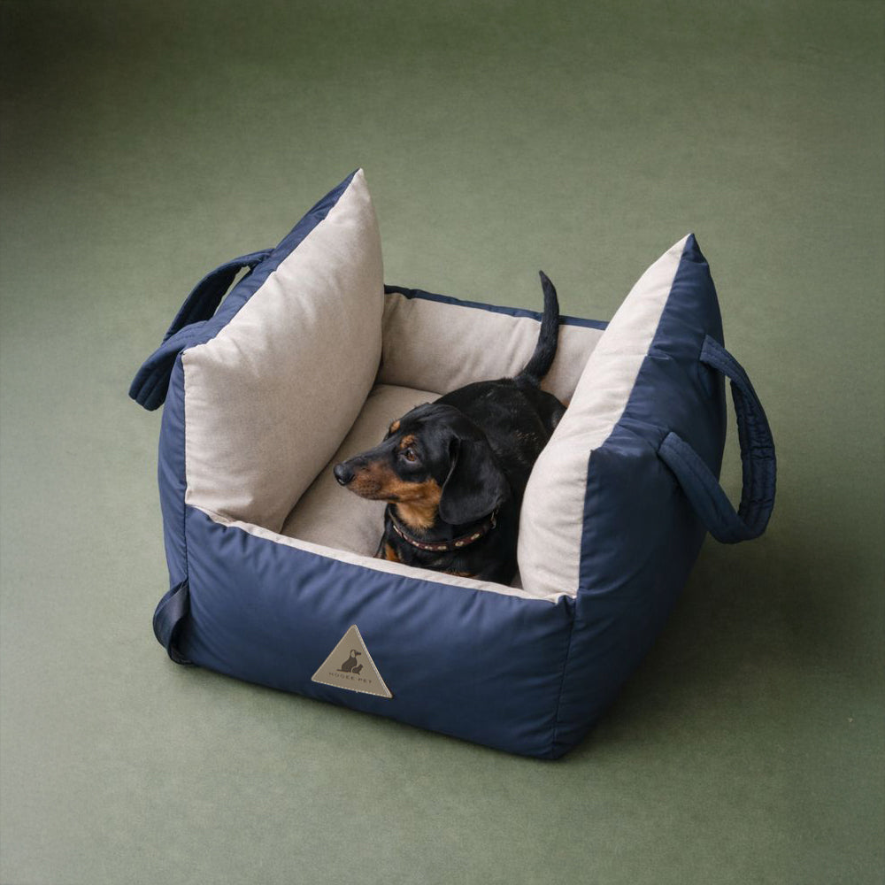 Small dog lounging in Nooee Pet Charlie car seat, a soft padded travel carrier and dog bed.