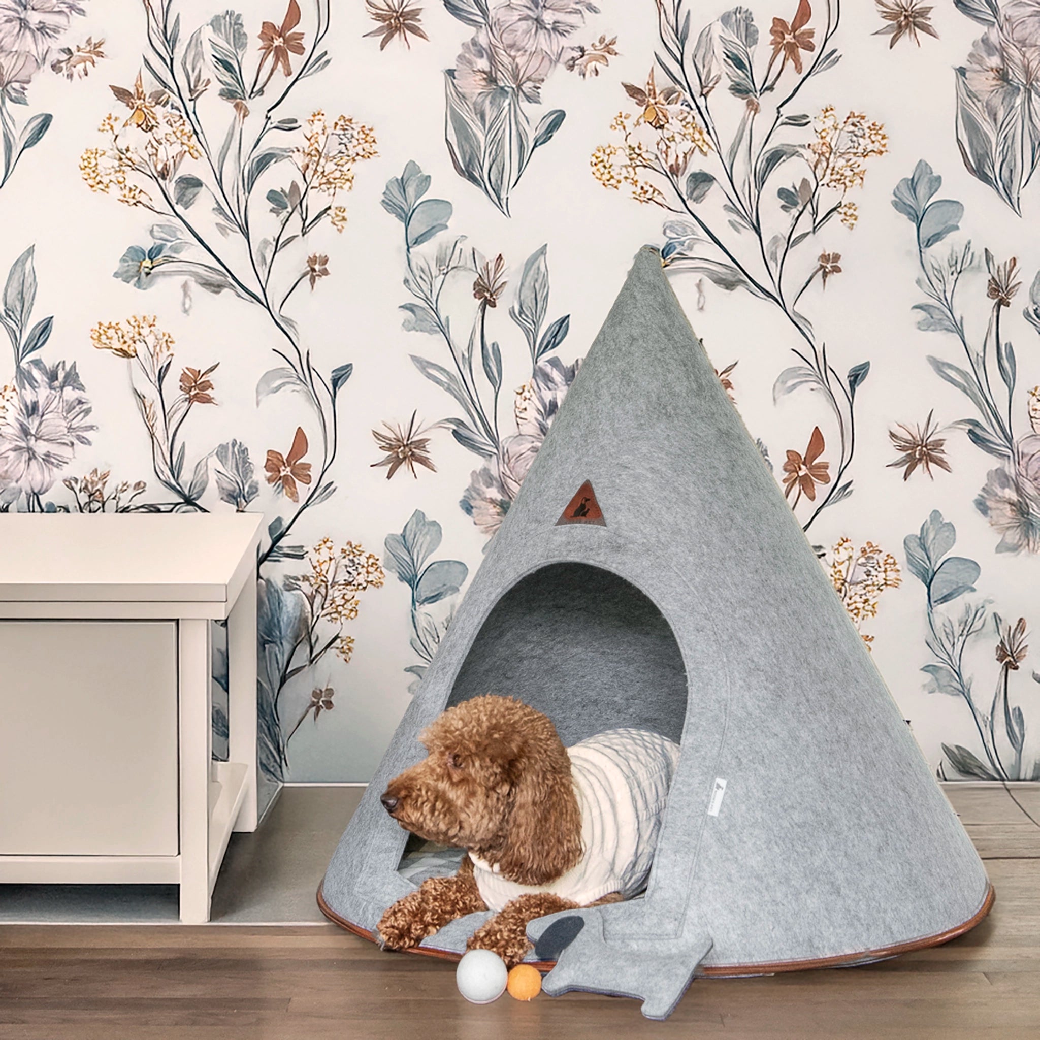 A cozy brown poodle resting inside the Nooee Pet Molly Cave (XL) against a stylish floral wallpaper.