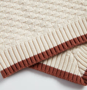 Close-up of Nooee Pet Organic Cotton Blanket showcasing the textured knit pattern and ribbed brown trim on cream-colored fabric.