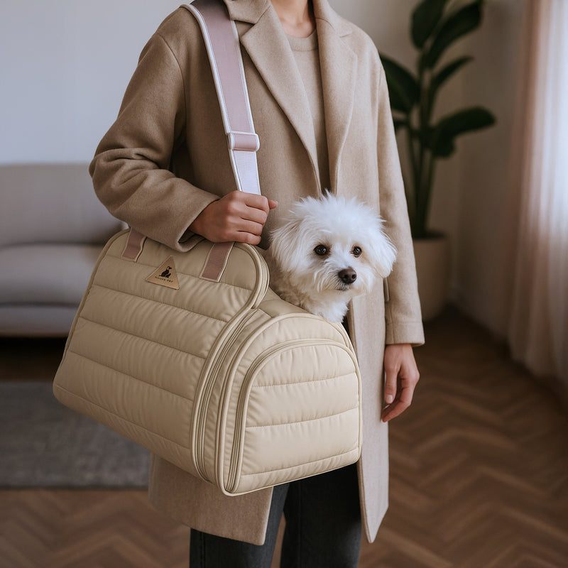 Small white dog riding in a cream Nooee Pet Oliver quilted pet carrier