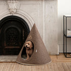 Brown Nooee Pet felt cave with a small dog sitting inside beside a fireplace