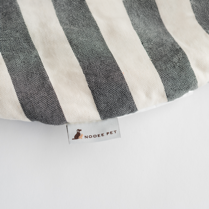 Close-up of the Nooee Pet Replacement Cushion in a black and cream stripe pattern, featuring a woven Nooee Pet brand label on soft cotton fabric.