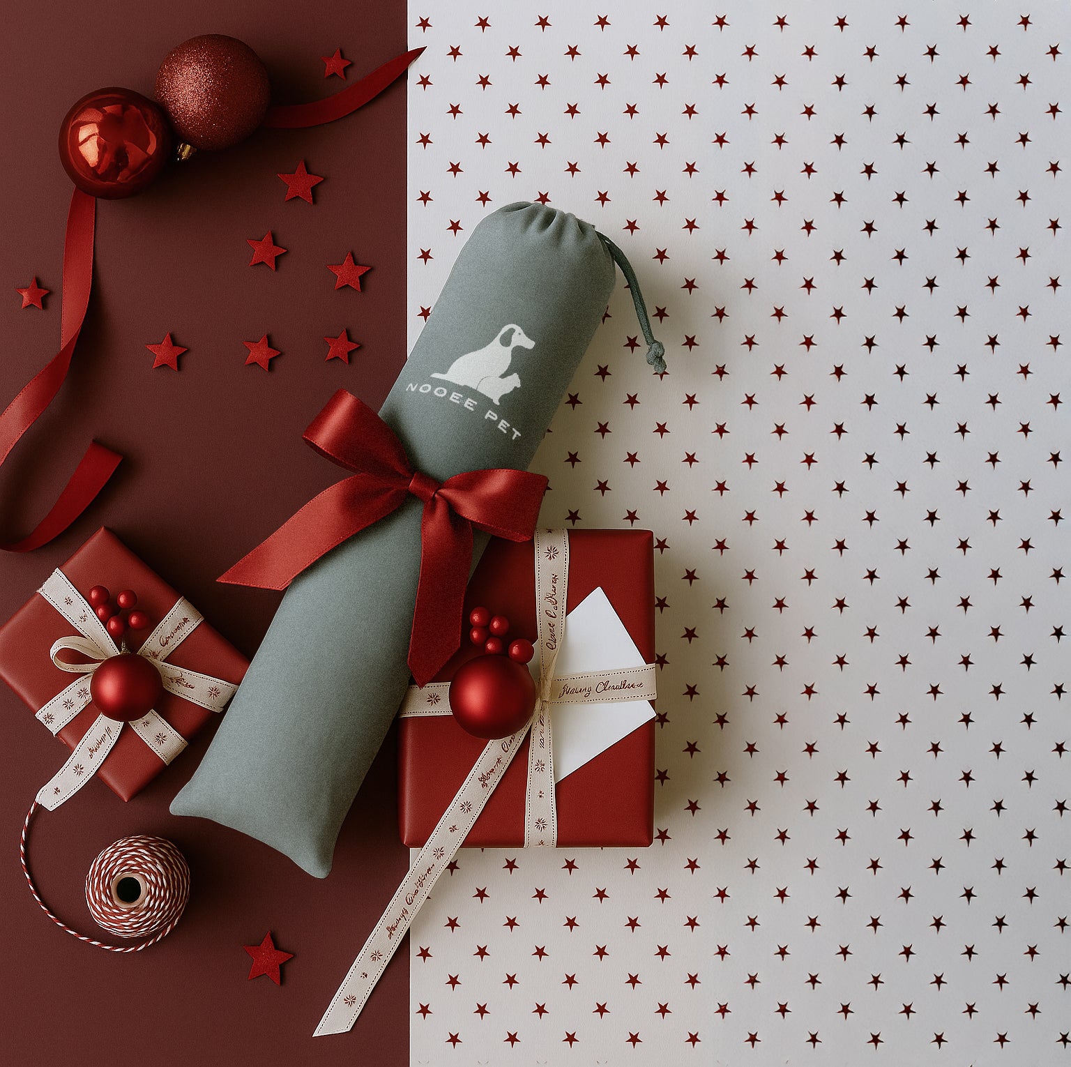 Holiday gift scene featuring a rolled Nooee Pet felt cave wrapped with a red ribbon, surrounded by red and cream gift boxes and festive ornaments on a star-patterned background.
