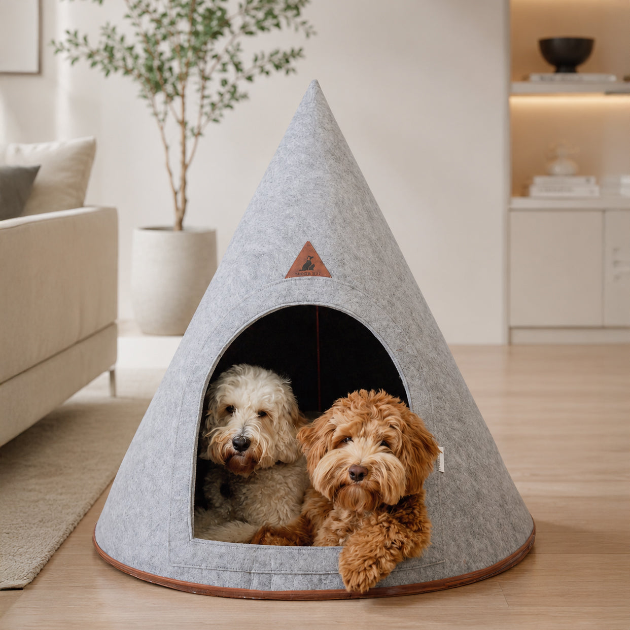 Two dogs resting inside a large gray felt pet cave in a modern living room
