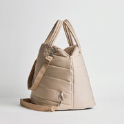 Side view of the Nooee Pet Lola Car Seat in cream nylon, showing adjustable shoulder strap, zippered closure, and soft quilted structure.