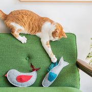Orange and white cat playing with a gray felt fish toy on a green upholstered chair, with a second gray felt bird toy featuring red wing and feathers nearby.






Orange and white cat playing with a gray felt fish toy on a green upholstered chair, with a second gray felt bird toy featuring red wing and feathers nearby.