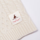 Close-up of the Nooee Pet x DEMYLEE New York collaboration label stitched onto the off white wool cable dog sweater.